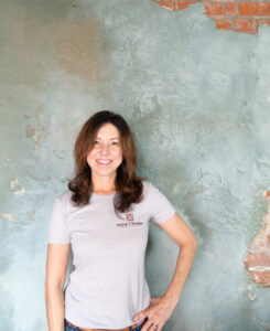 Sylvia Thompson-Dias - Founder and Co-Owner of Sylvia T Designs in an historic New Orleans Creole Cottage in the French Quarter in front of her plaster work.